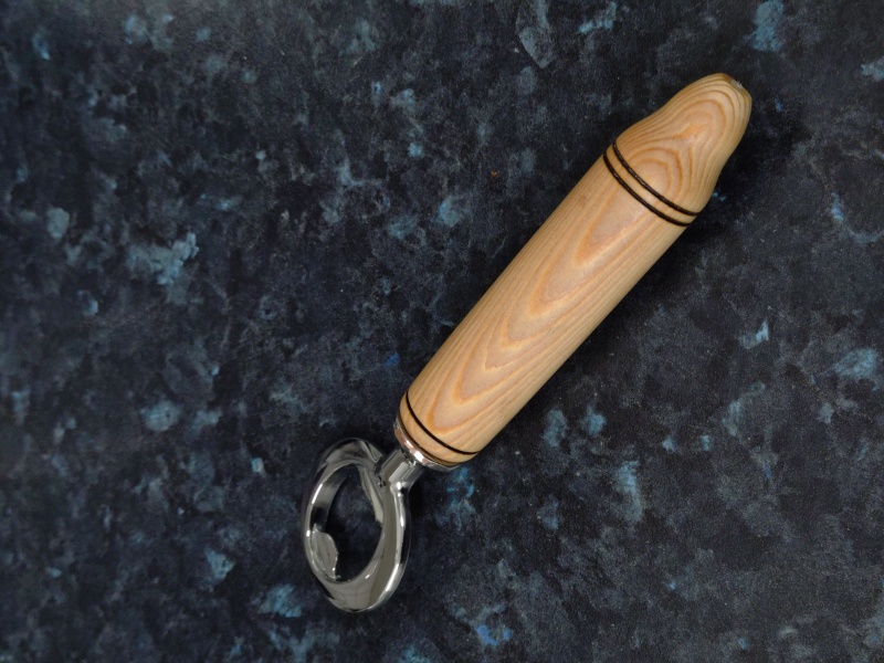 Bottle opener with a turned Ash handle with burned ring motif. The handle is finished with friction wax.